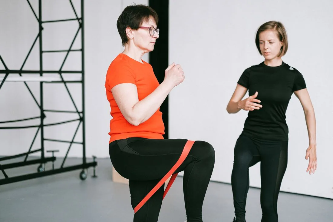 Une personne effectue un exercice avec une bande élastique, accompagnée par une coach