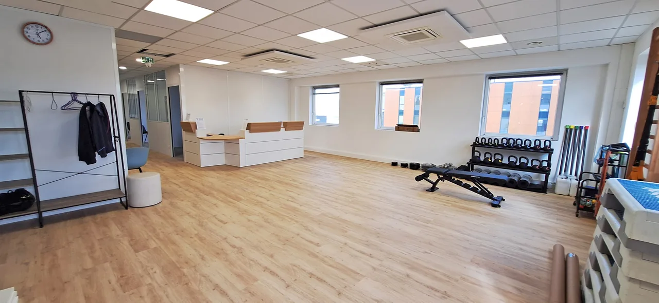 Accueil et espace ouvert avec tapis, haltères et accessoires de mobilisation.