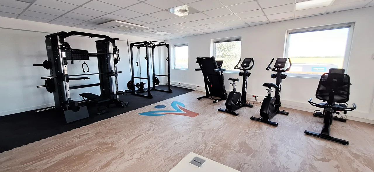 Espace de renforcement avec racks, vélos et appareils de cardio à Vitalyste Plaisir.